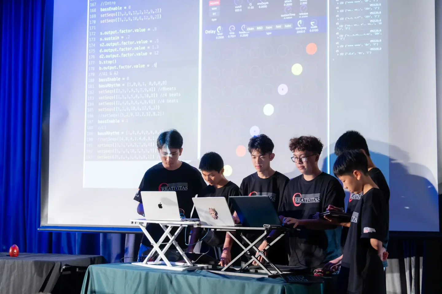 Students performing music with laptops on stage